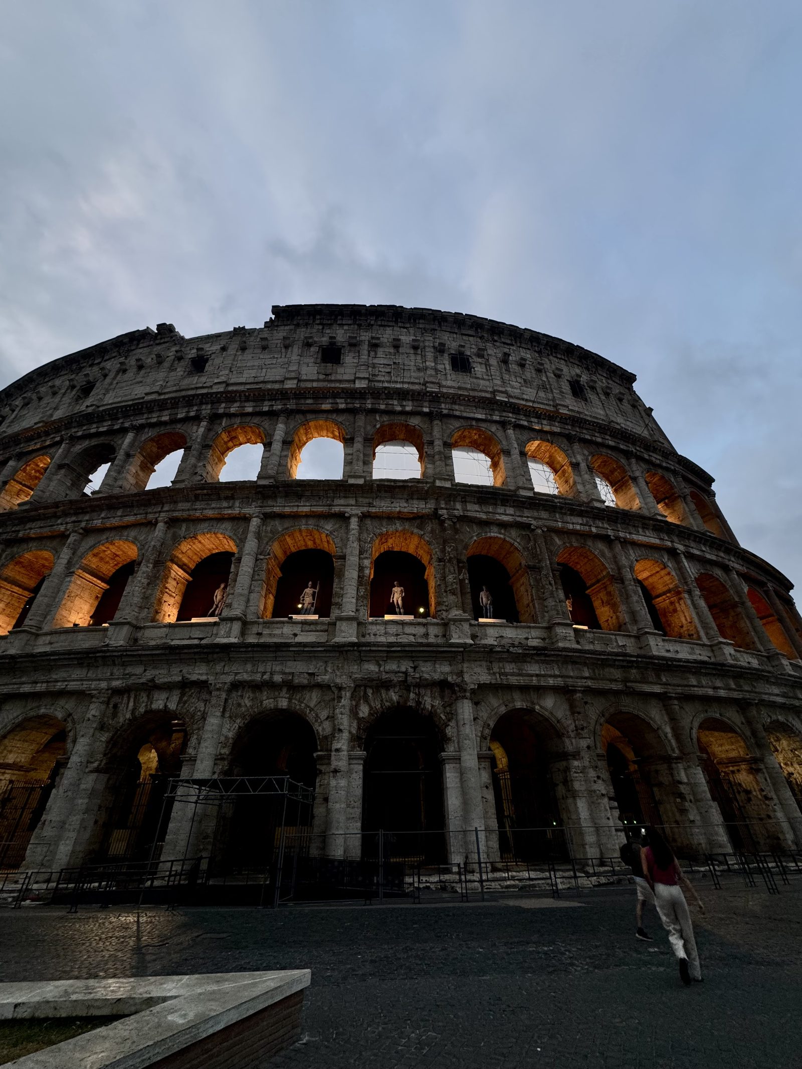 The Roman Colosseum lit warm against an evening sky