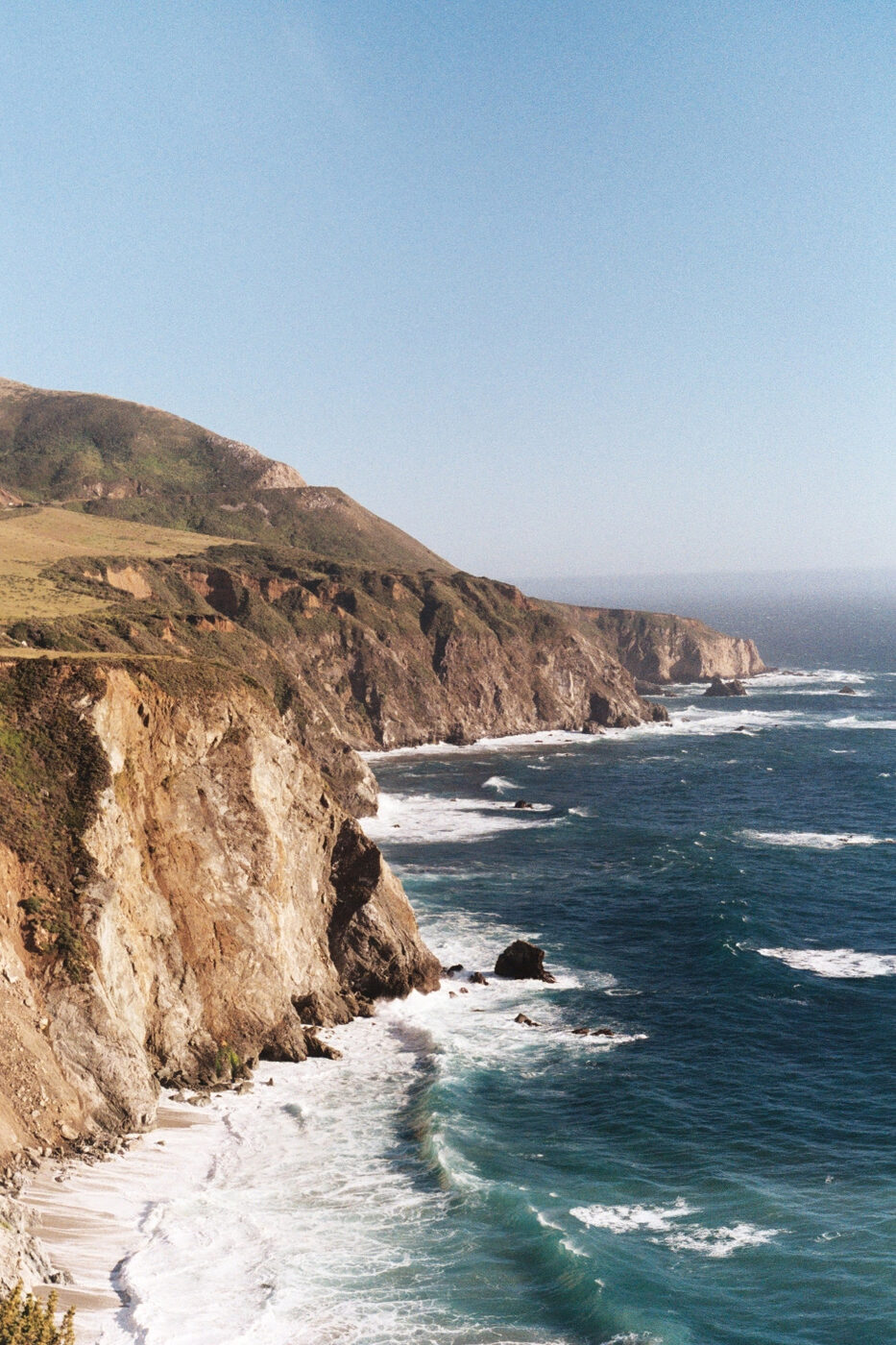 Waves breaking along the sunlit Big Sur coastline